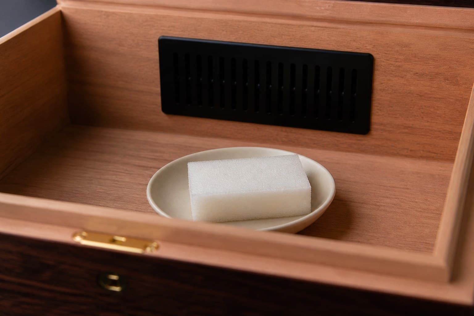 Distilled-water sponge on a dish inside an empty cedar humidor for seasoning